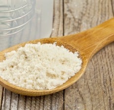 whey protein concentrate powder in a wooden spoon