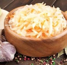 Sauerkraut with carrot in wooden bowl garlic spices cabbage on a cutting board