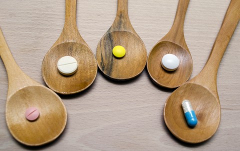 Different pills and tablets on wooden spoons 
