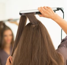 woman using a hair straightening iron